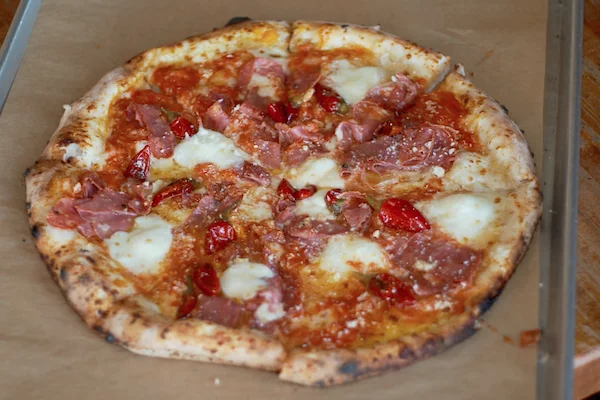 Antico pizza with meats, peppers, and cheese