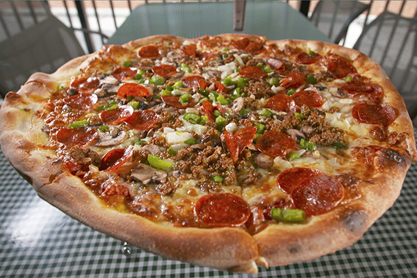 Pizza pie with pepperoni, peppers, onions, mushrooms, sausage, and cheese