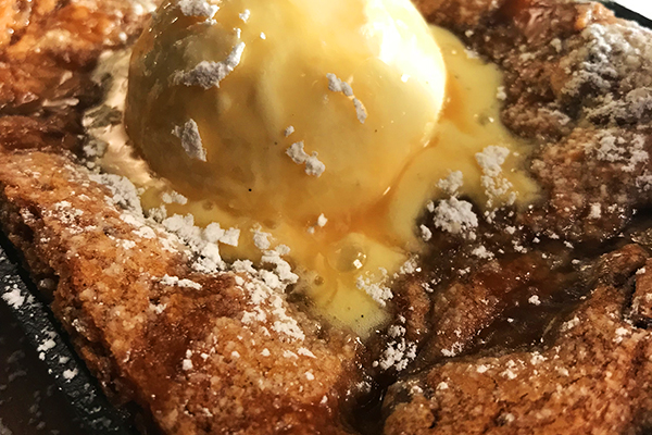 a skillet baked chocolate chip cookie topped with a scoop of ice cream