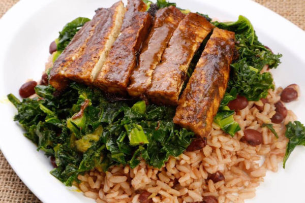 Avocado Vegan Cafe - Kale In coconut sauce over Rice & Beans, topped with Jerk Tofu | Photo: Facebook/avocadovegancafe