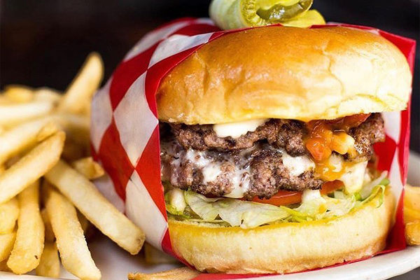 Burger wrapped in red butcher paper and french fries