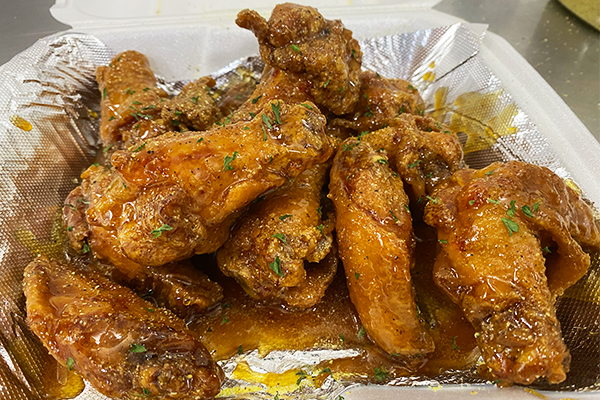 Hot honey lemon pepper wings in a container with foil