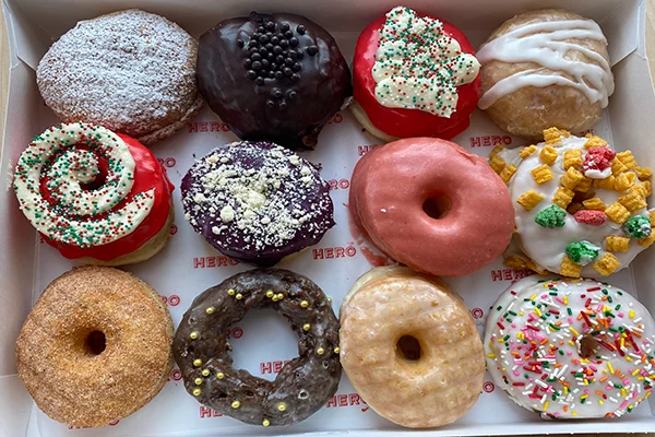 A dozen donuts of varying shapes, colors, and toppings