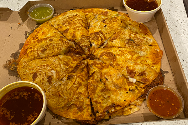 A tortilla stuffed with birria meat and cheese and crisped up and served with several sauces