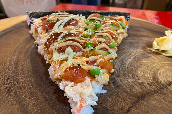 Sushi pizza topped with tuna, edamame, and a drizzle of spicy mayo