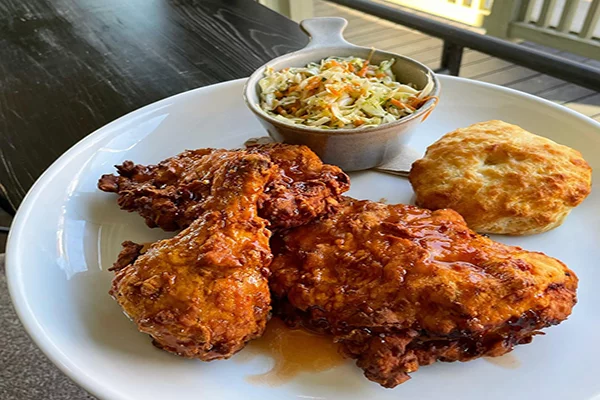 Plate of fried chicken with a biscuit and slaw in the background
