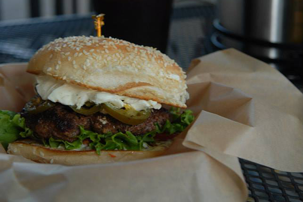 A cheeseburger with jalapenos and other toppings