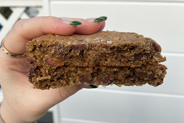 Cookie broken in half, with chocolate chunks, coffee, oats, pecans, and coconut and a sprinkle of salt on top