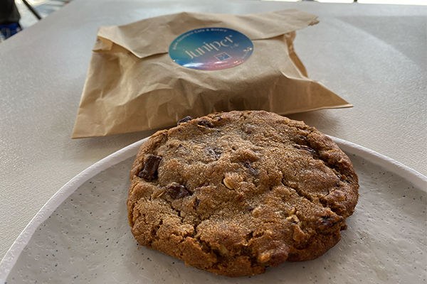 Cookie with chocolate chips, pecans, and oatmeal from Juniper Cafe, with cookie sleeve in background