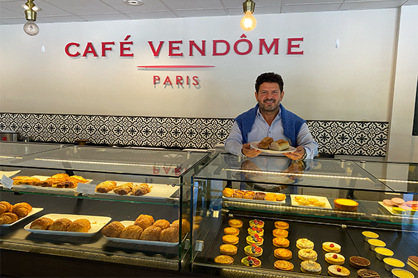 Man holding sandwich next to pastry display