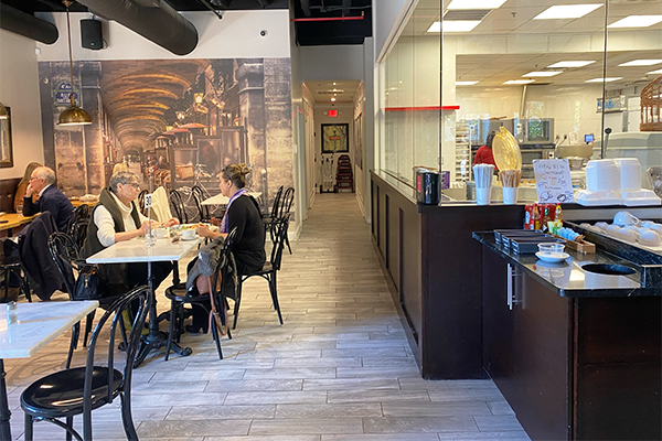 Customers sitting in Cafe Vendome with mural in background and bakery behind them