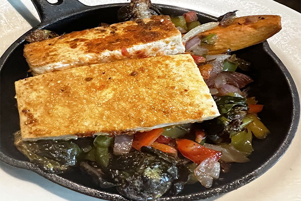 Skillet with veggies and two pieces of tofu