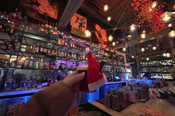 holding a drink up at holiday bar in west midtown 