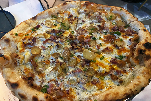 Pizza with potato, green onions, bacon, and cheese