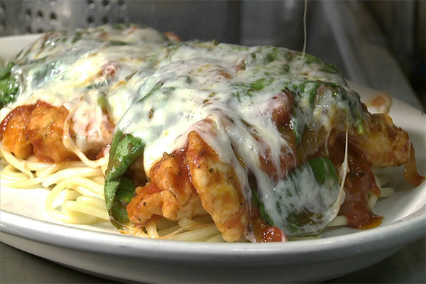 Chicken with basil and melted cheese over noodles