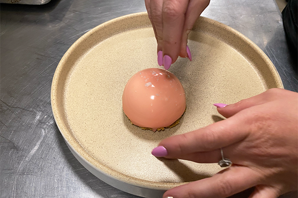 Hand adding salt to a pink blood orange mousse