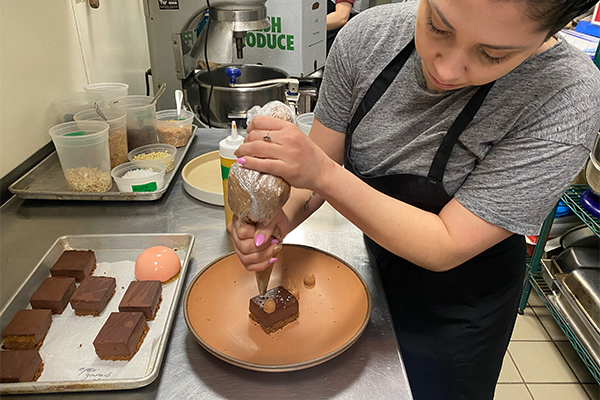 Woman adding dollops of chocolate to a chocolate dessert