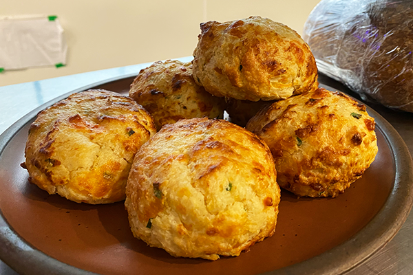 Pile of cheddar chive biscuits on a brown plate