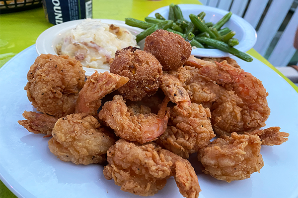 Fried shrimp platter with hush puppies, mashed potatoes, and green beans