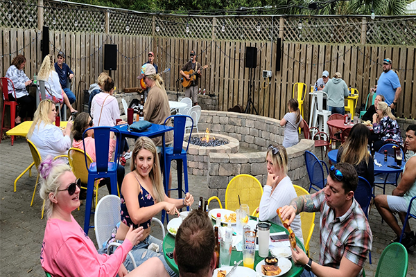 Customers dining in patio with firepit and live music in background