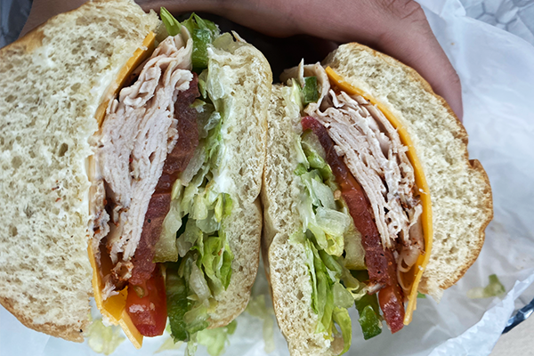 Close-up of turkey sub with lettuce, tomato, pickles, and mayo