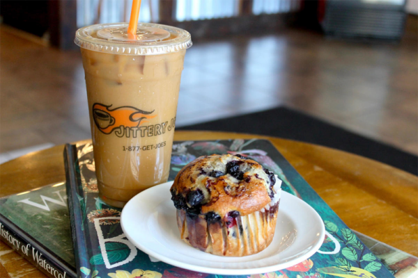 Muffin on dish with iced coffee in background