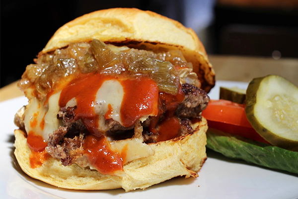 Cheeseburger with caramelized onions and a side of lettuce, tomatoes, pickles