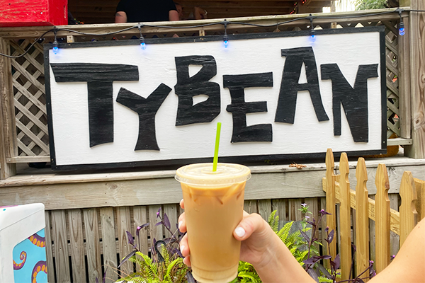 Iced coffee drink held up to sign saying "Tybean"