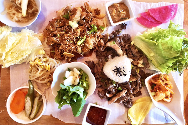 Korean food platter including bulgogi, spicy pork, and various snacks and garnishes