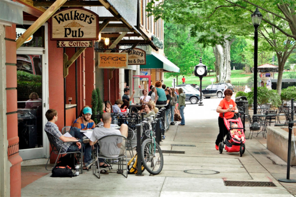 City block with Walker's Pub & Coffee in foreground and groups of people sitting outside