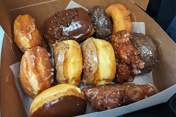 Three rows of donuts in a box lined with parchment paper