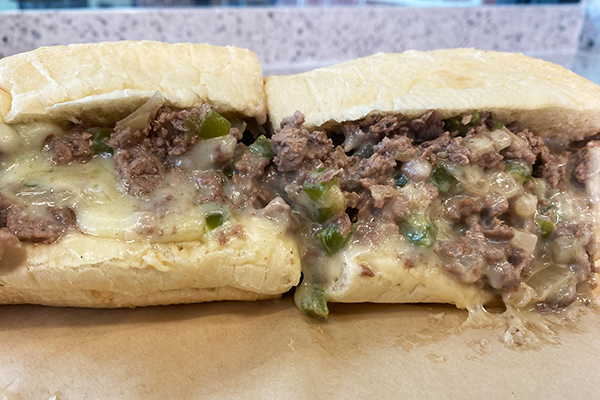 Close-up of cheesesteak with sliced steak, onions, green peppers, and cheese