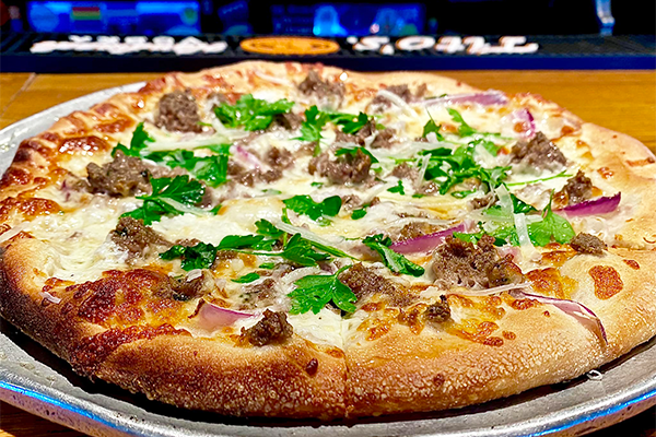 Close-up of pizza with meatballs, red onions, and parsley