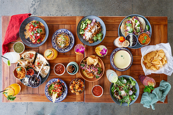 Overhead shot of a table full of salsas, tacos, sides, cocktails, and more
