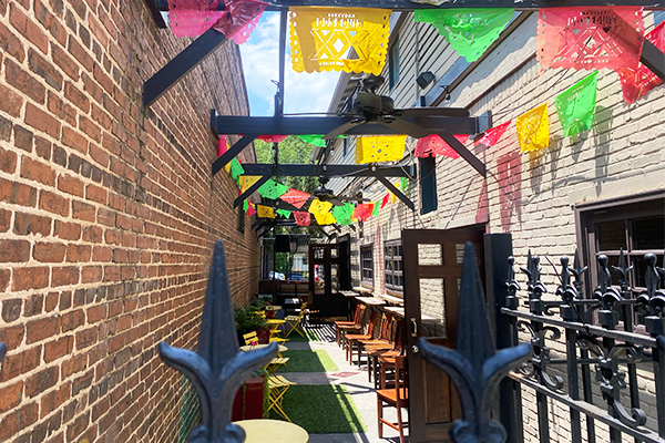 A patio with green turf, yellow and brown chairs, and Dos Equis banners hanging across the walls