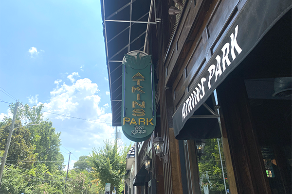 A green sign, reading "Atkins Park" in yellow set upon a blue sky