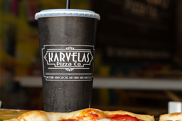 Black cup saying "Karvelas Pizza Co. Not real glamorous but dang sure delicious"
