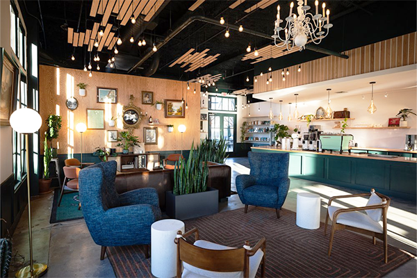 Coffee shop with chairs, couches, lights, and a coffee bar in the background