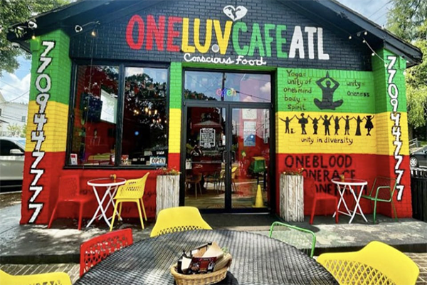 A restaurant with green, yellow, red, and black paint saying "One Luv Cafe ATL: Conscious Food" across the top